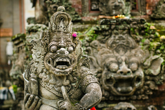 A traditional statue of a guard demon carved out of stone stands in the street on the island of Bali, Indonesia.