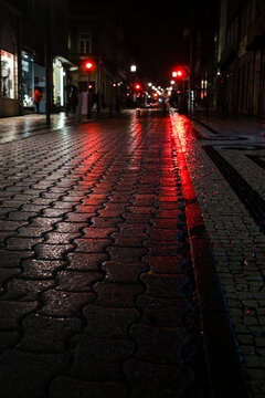 A wet sidewalk at night in the lights in the center of the old city of Porto, Portugal.