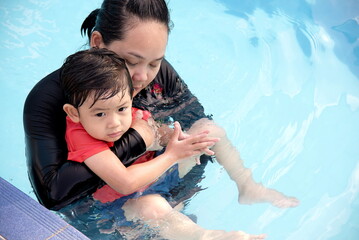Little asian boy and his mother playing in swimming pool