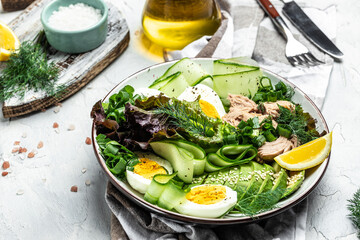 Tuna vegetable vegetarian buddha bowl avocado, egg, cucumber and fresh salad on a light background. top view