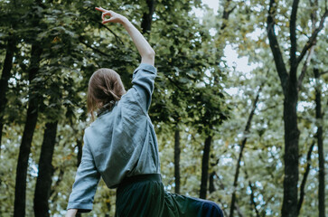 Woman doing yoga peaceful warrior pose in early autumn forest