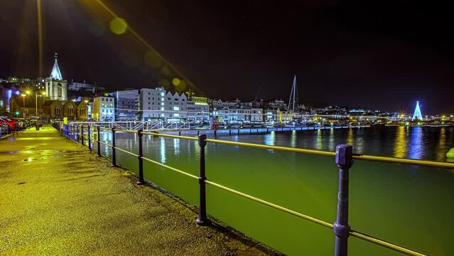Illuminated Landmarks On St Peter Port Harbour In Guernsey. Picturesque Night View From Promenade. hyperlapse