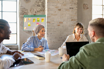 Young multiracial team of creative colleagues working in a open space, muslim business woman with...