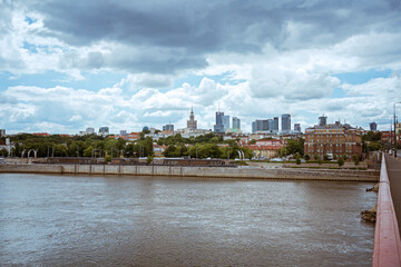 Obraz premium Cloudy day of the big city in Warsaw in summer, Poland skyscrapers of tall buildings on the horizon above the surface of the Vistula river. city ​​panorama beautiful cityscape