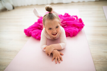Little girl with down syndrome at ballet class in dance studio,lying and resting. Concept of...