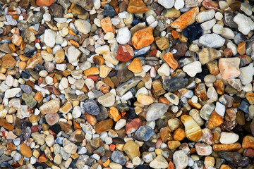 Blick von oben Draufsicht auf verschiedenfarbige Steine Kieselsteine im Wasser am Strand, horizontal 