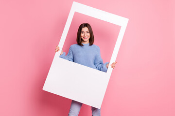 Photo of adorable charming young woman wear blue sweater holding white photo frame isolated pink...