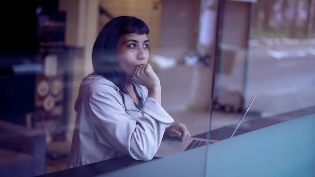 South American young woman thinking of an idea while working in front of laptop. A Brazilian adult girl having eureka breakthrough at business workplace