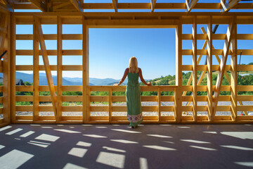 Senior woman on site inside construction framing dreaming of her new home and looking at view.