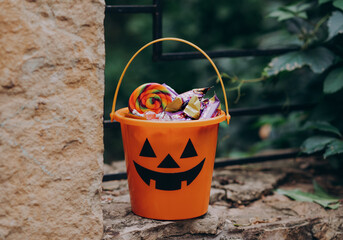 Halloween Jack o Lantern orange bucket with candy and sweet treats outdoor - obrazy, fototapety, plakaty