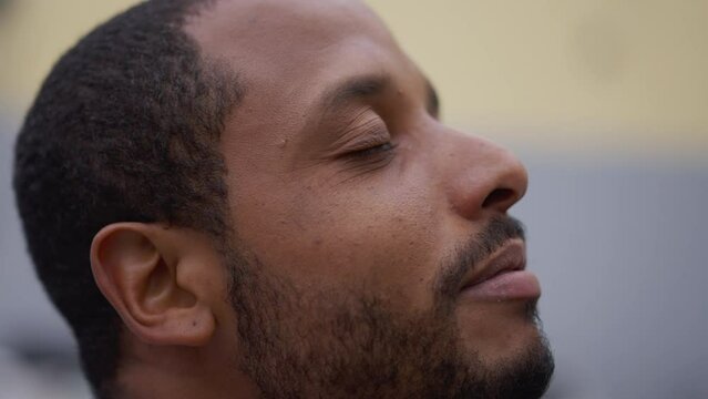 Spiritual young African American man closing eyes in contemplation. Brazilian person opening eye to sky with HOPE and FAITH