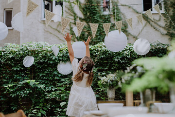 Rear view of happy little child playing with wedding decorations.