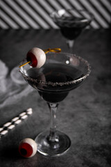 Halloween black cocktail in glasses with candy eyeball. Party festive celebrate concept.