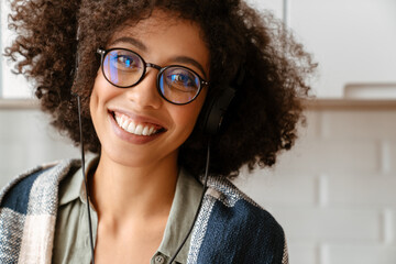 African american woman with afro hairstyle using earphones at home