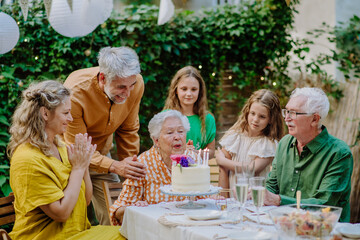 Multi-generation family on outdoor summer garden party, celebrating birthday