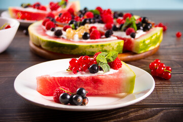 Colorful summer watermelon piece of cake with whipped cream and berries. Refreshment summer dessert food.