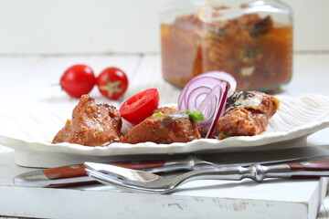 Catfish canned in a tomato in a glass jar on a white background	
