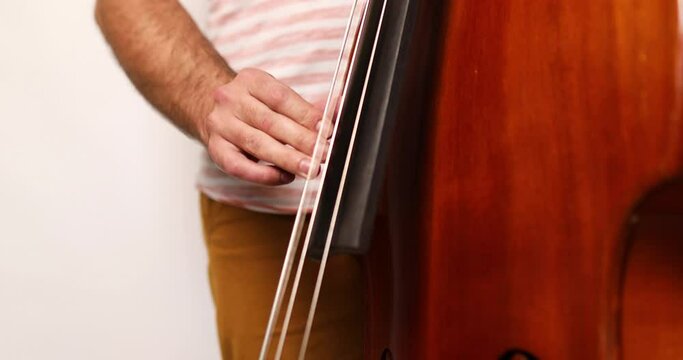 Double Bass Player Man Playing Classic Wooden Violoncello Or Contrabass On White Background, Relaxing With Song And Music. Practicing In Playing. Lifestyle Concept.