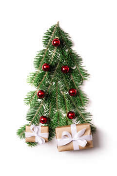 Decorated Christmas tree created from fir twigs with red christmas balls and presents for new year isolated on white background. Gift boxes with white ribbons under Christmas tree