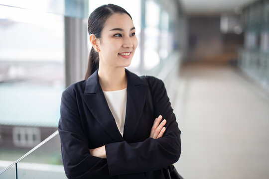 Asian business woman smilng looking away, Fashion business photo of beautiful girl in casual suite with blurred building background.