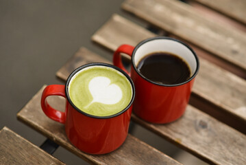A cup of coffee and a cup of matcha on a table in a cafe