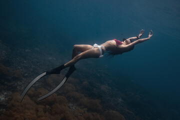 Female freediver fun diving in the ocean sea posing holding breath