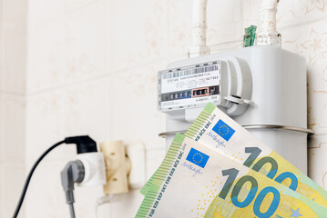 Fototapeta na wymiar A gas meter in the house.Euro banknotes near.Counter for distribution domestic gas. Symbolic image of a payment for heating and electricity in winter.Selective focus.