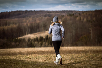 Woman running in autumn nature. Fitness activity outdoors