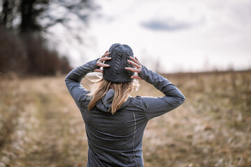 Female athlete puts on hat in cold weather before running outdoors
