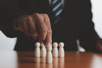 Hands of businessmen choose wooden dolls. The concept of choosing leaders for business success. Organization development. Leadership. Personnel selection. Wooden puppet. Wooden peg dolls.