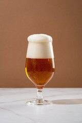 One glass amber golden beer overflowing food and drink