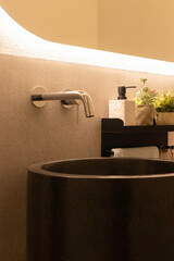 Vertical view of modern bathroom with black natural stone pedestal sink and built-in wall faucet