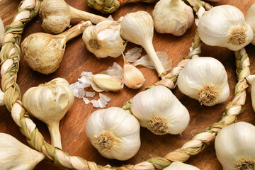 braided garlic heads and cloves on a rustic wooden background, delicious and healthy food