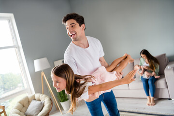 Photo of positive excited couple two kids father holding hands arms daughter having fun indoors house home room