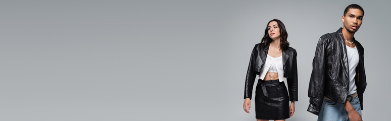 young interracial couple in stylish autumnal outfits posing isolated on grey, banner.
