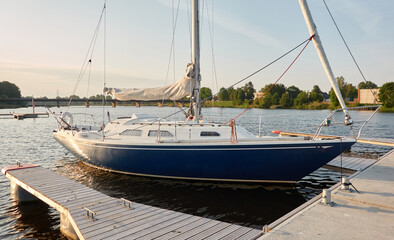 Fototapeta na wymiar Sloop rigged sailboat (for rent and sale) moored to a pier in a yacht marina. Nautical vessel, transportation, amateur sailing, vacations, cruising, recreation concepts