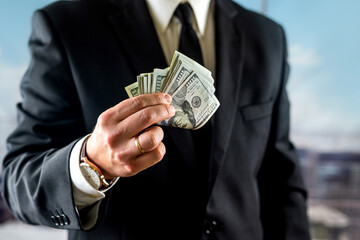 businessman man counts his profit for the month in his hands.