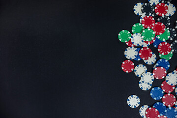 colored casino poker chips scattered on a black table.