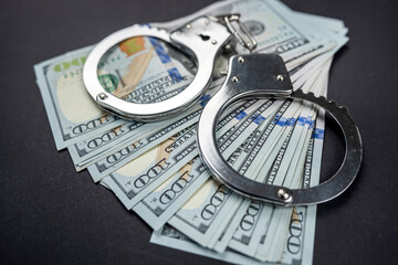 Banknotes dollars money and handcuffs isolated on black background.