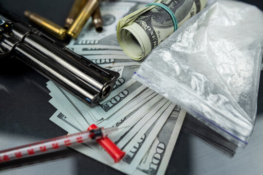 couple of dollars in gun on isolated on black table with syringe and cartridges.