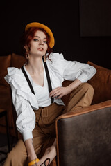 A beautiful girl in a white shirt and suspenders. Posing