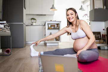 Pregnant woman exercising in living room at home.