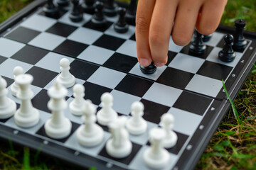 Child playing chess on the lawn. Little boy makes first move and developing chess strategy, play...