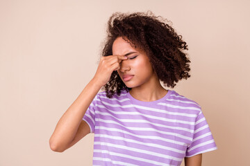 Photo of tired unhappy girl dressed purple t-shirt closed eyes arm nose isolated beige color...