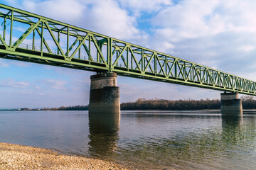 a green railroad bridge over a river