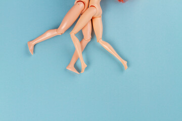 Fototapeta Pair of naked doll bodies on blue background. Legs of hugging couple. obraz