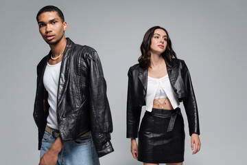 young interracial couple in stylish autumnal outfits posing isolated on grey.