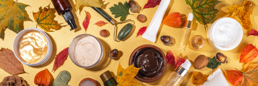 Set Various Nourishing Moisturizing Anti-aging Autumn Facial Skin Care Cosmetics. Serum Bottle, Cream, Scrub, Organic Beauty Care With Autumn Leaves, Decor, Warm Sweater, On Golden Yellow Background