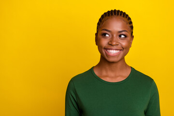 Photo of dreamy sweet young lady dressed green shirt looking empty space smiling isolated yellow color background
