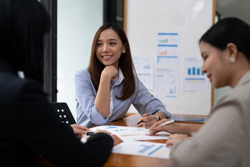 A young asian woman is having a business meeting with her team colleagues in a conference room.